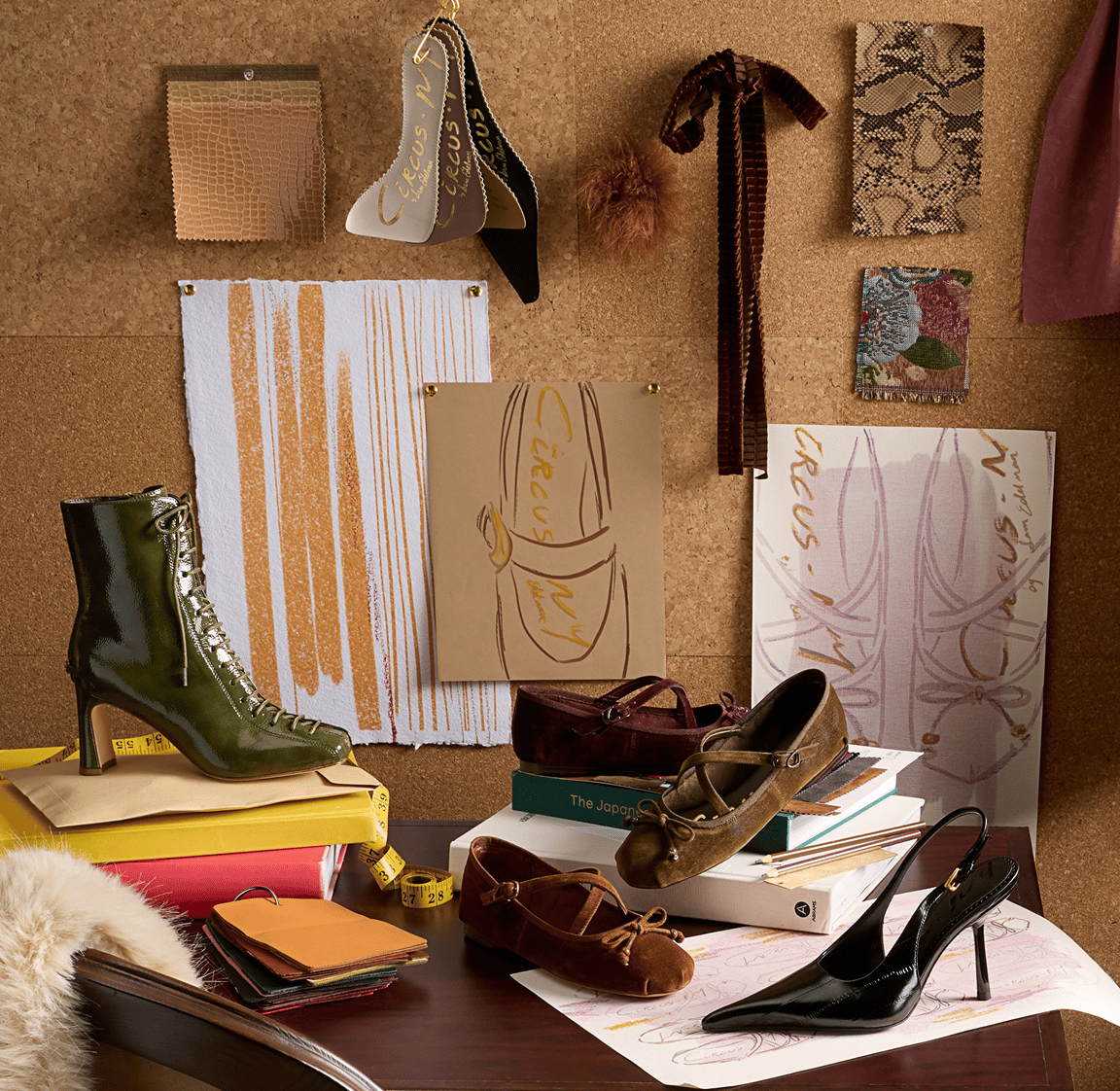 A design studio desk displaying Circus NY shoes: a green boot, black slingback pump, and suede Mary Jane flats.