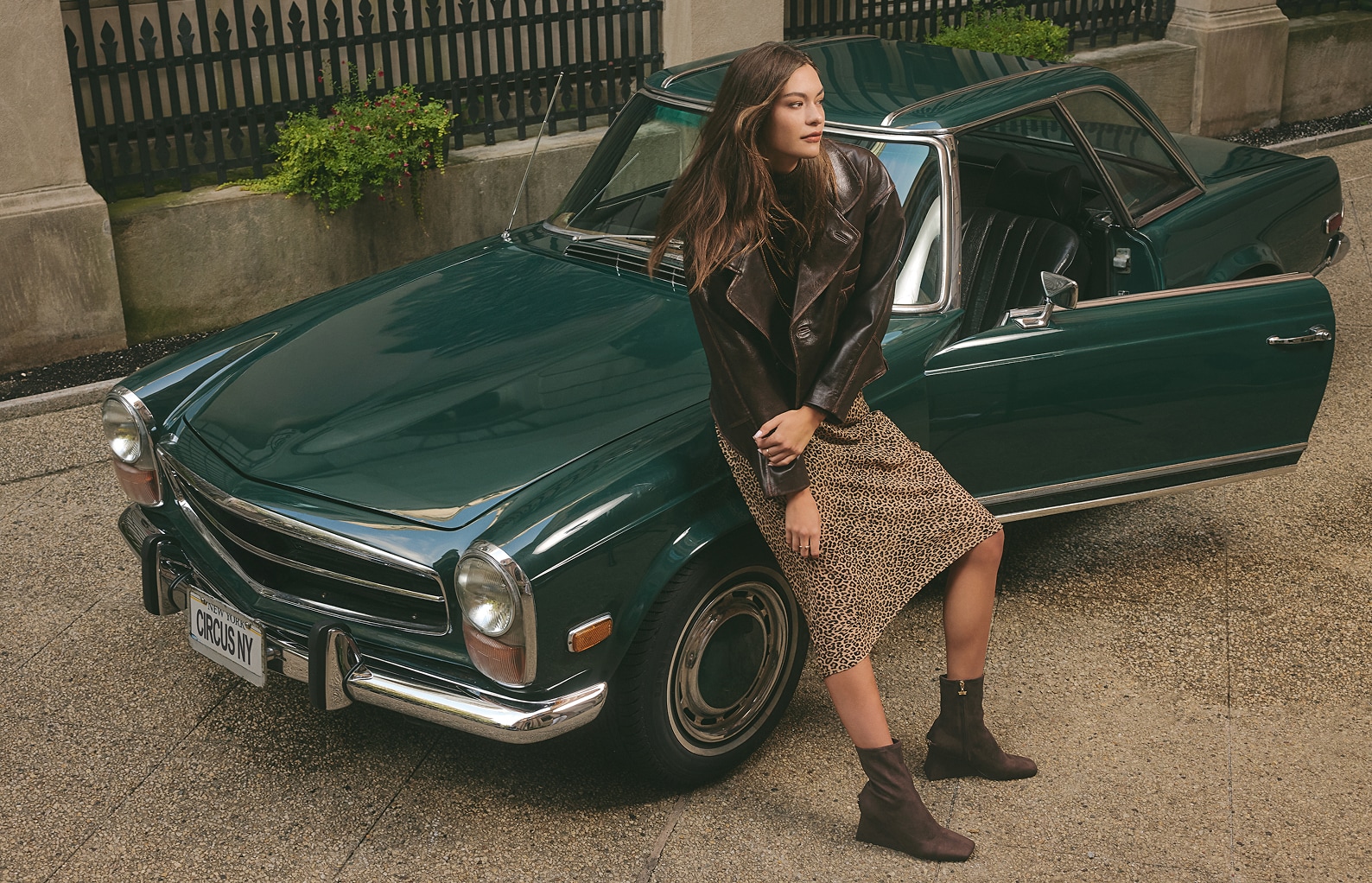 woman leaning against a vintage car while wearing the lia wedge bootie in dark chocolate