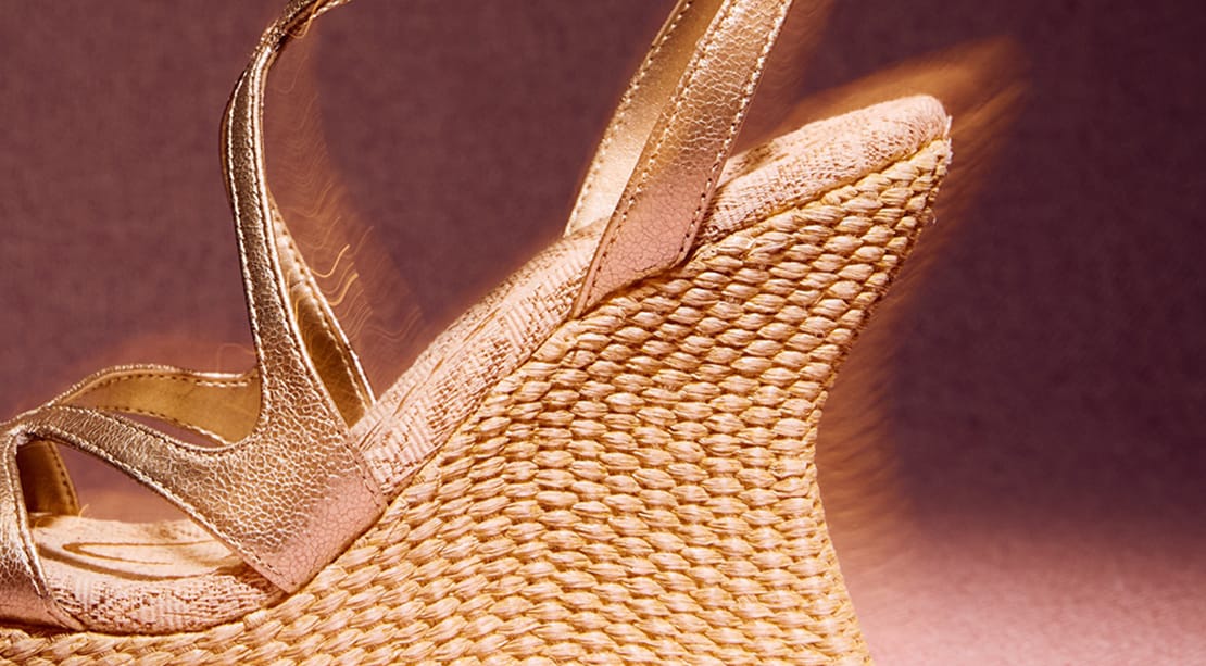 Close-up of the Trina Platform Wedge Sandal in metallic gold faux leather with a woven heel.