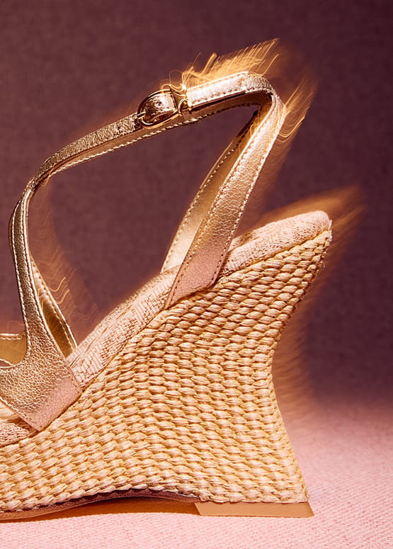 Close-up of the woven heel and slingback strap on the metallic gold faux leather Trina Platform Wedge Sandal.