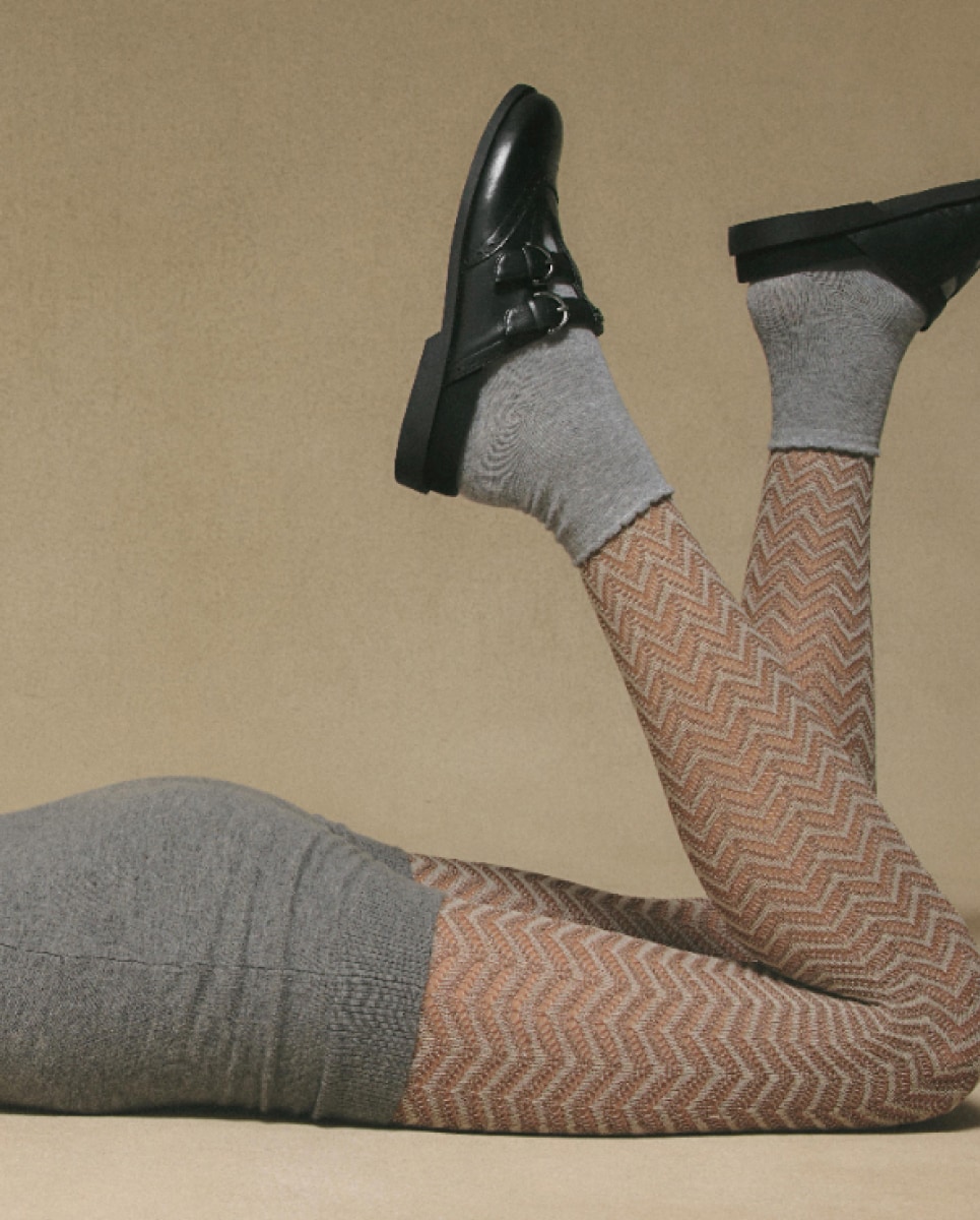 woman wearing down laying wearing the claudia clog in black with grey socks